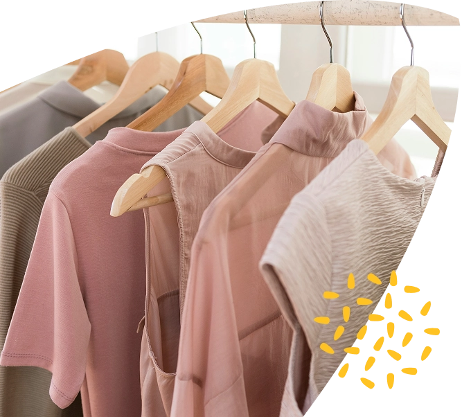 Five neutral-toned shirts and blouses on wooden hangers are hanging on a rail, creating a serene and inviting display. The clothing is arranged neatly, with soft lighting highlighting each piece, while a curved white shape with yellow dots in the corner subtly nods to the warm support offered by Mayo Roscommon Hospice.